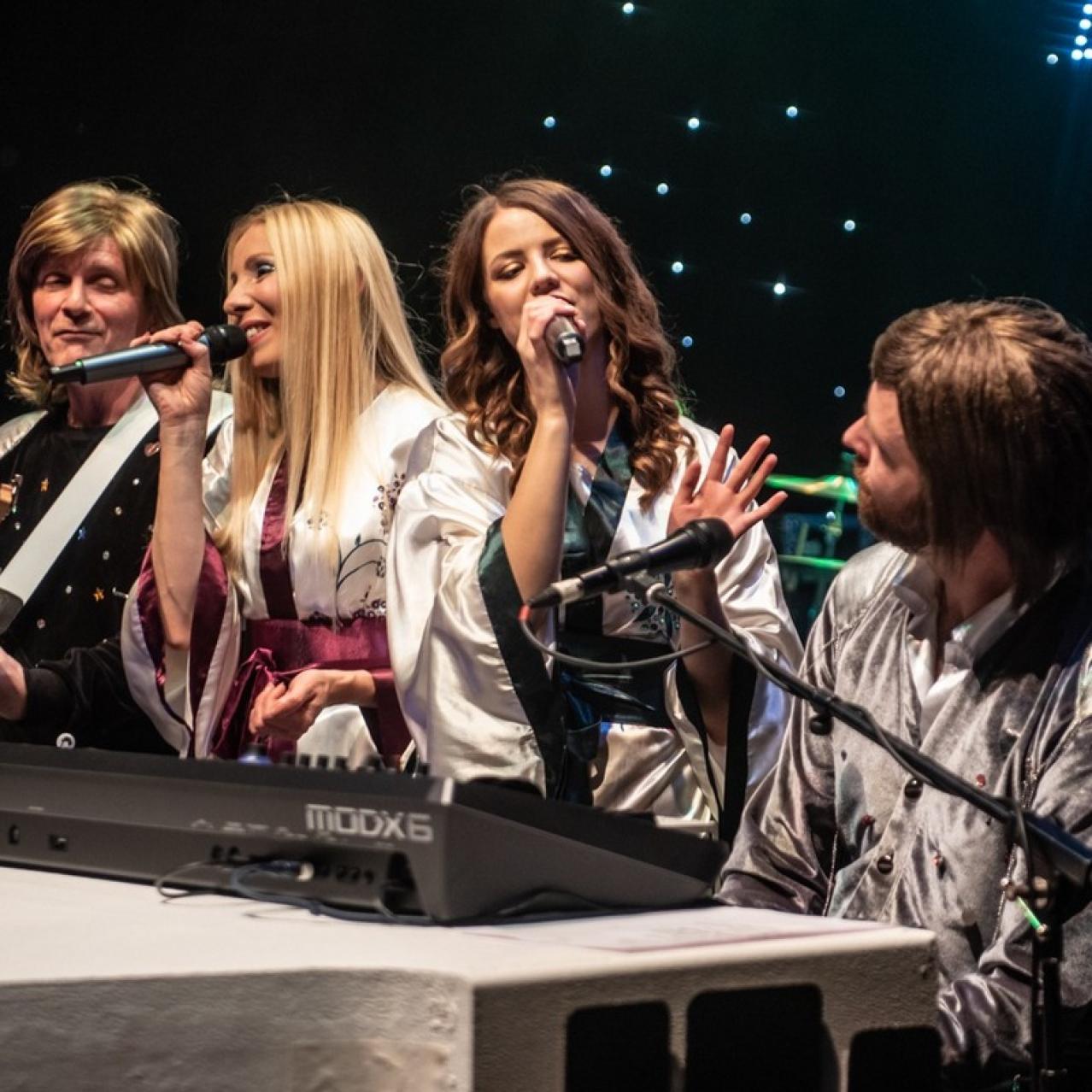 All 4 band members of Abba sitting at the piano